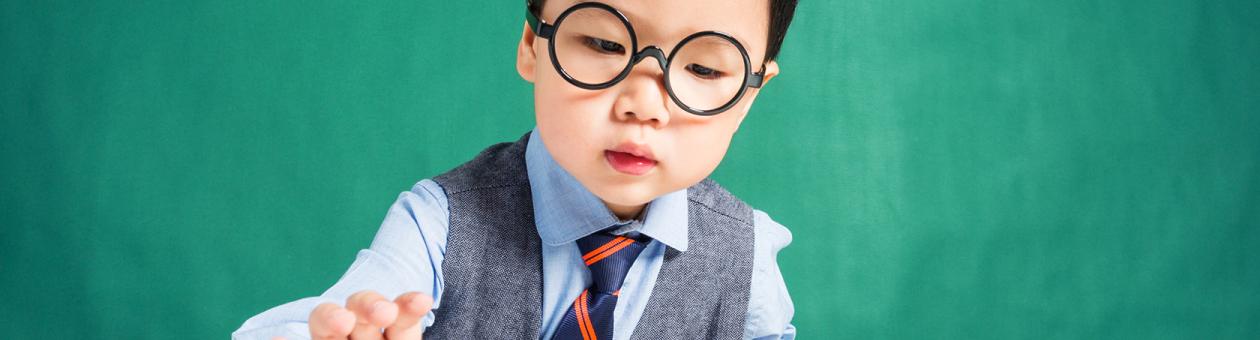 Ein kleine Junge mit Brille greift nach einem Geldstapel beim Zählen